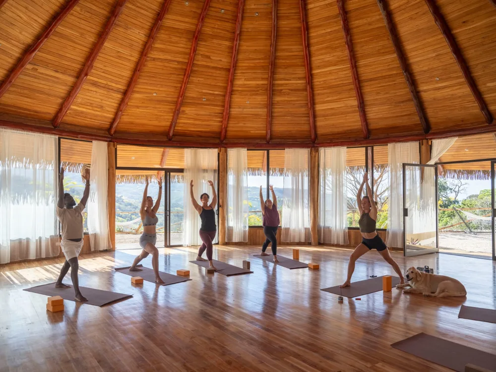 Guests practicing yoga in an open-air pavilion